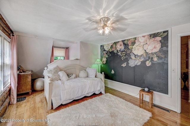 bedroom featuring multiple windows, light hardwood / wood-style floors, and ceiling fan