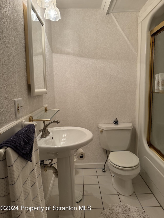 bathroom with tile patterned floors, toilet, and combined bath / shower with glass door