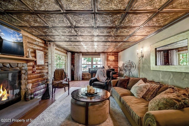 living room with log walls, hardwood / wood-style floors, and a stone fireplace