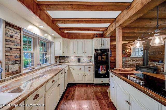 kitchen with beam ceiling, a wood stove, rustic walls, and white cabinetry