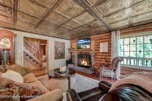 living room with log walls, wood-type flooring, and a stone fireplace