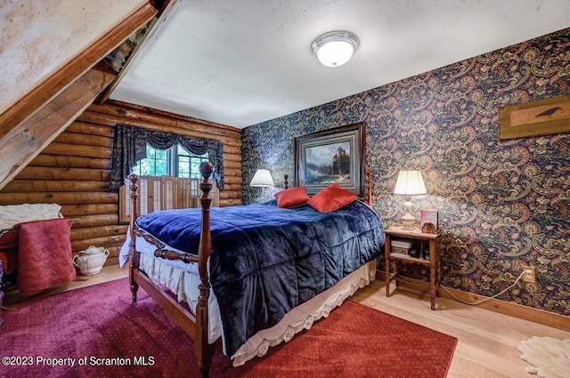 bedroom with rustic walls, hardwood / wood-style floors, and a textured ceiling