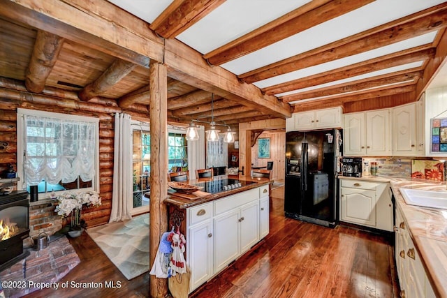 kitchen featuring rustic walls, black appliances, decorative light fixtures, beamed ceiling, and white cabinetry