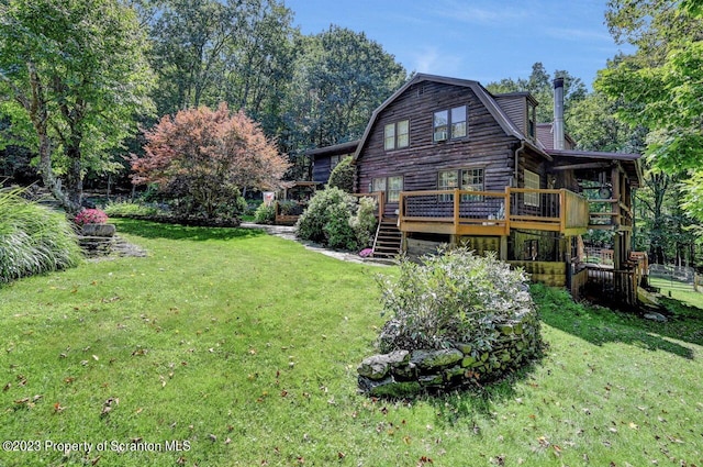 rear view of house featuring a lawn and a deck