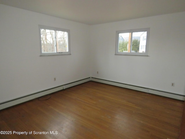 spare room with a baseboard radiator, plenty of natural light, and dark hardwood / wood-style flooring