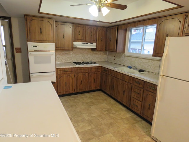 kitchen with sink, white appliances, ceiling fan, backsplash, and a raised ceiling