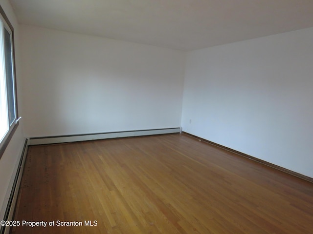 empty room with a baseboard heating unit, light hardwood / wood-style floors, and a healthy amount of sunlight