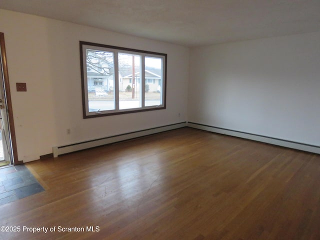 empty room featuring wood-type flooring and a baseboard heating unit