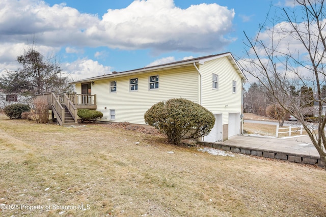 rear view of house with a yard, a deck, and a garage