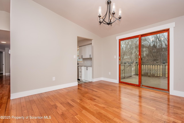 unfurnished dining area featuring a notable chandelier, light hardwood / wood-style floors, and lofted ceiling