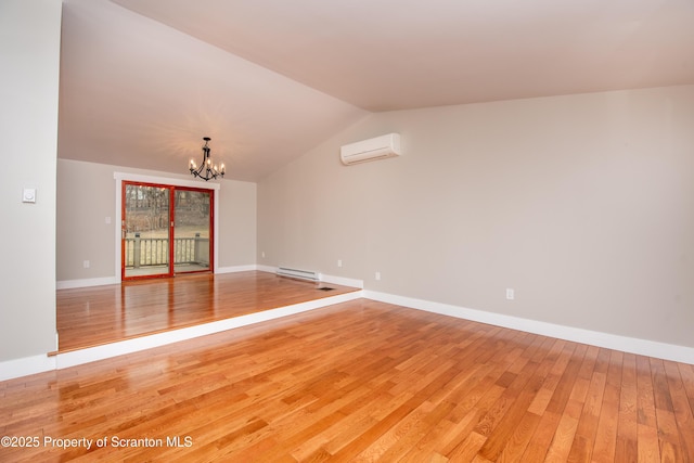 spare room with hardwood / wood-style flooring, lofted ceiling, baseboard heating, a wall mounted air conditioner, and an inviting chandelier