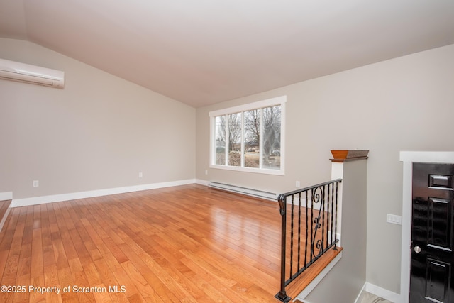 spare room featuring an AC wall unit, lofted ceiling, a baseboard heating unit, and hardwood / wood-style floors