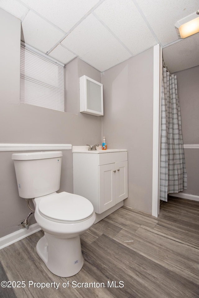 bathroom with a paneled ceiling, toilet, vanity, and wood-type flooring