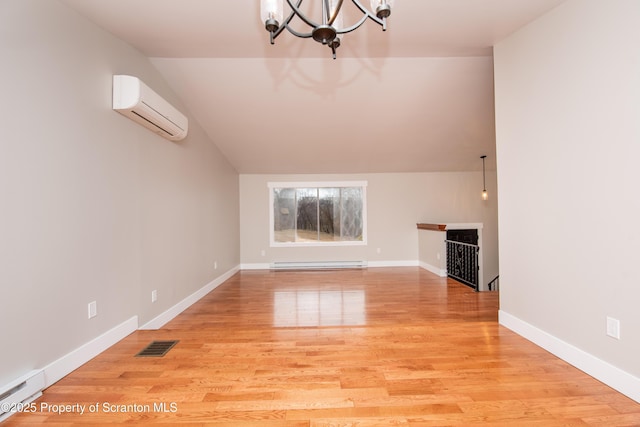 unfurnished living room with a wall unit AC, a chandelier, a baseboard heating unit, and light hardwood / wood-style floors