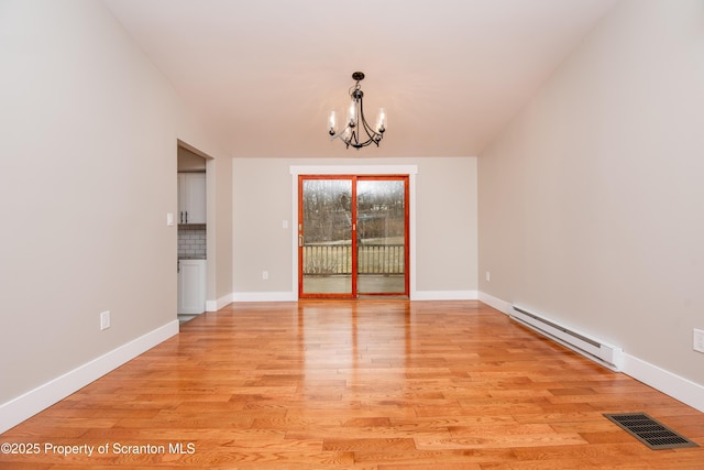 empty room featuring light wood-type flooring, a chandelier, and a baseboard heating unit