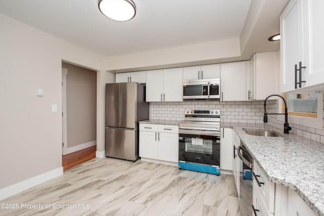 kitchen with sink, white cabinets, light stone countertops, and stainless steel appliances