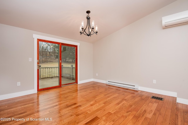 empty room with a wall mounted air conditioner, baseboard heating, wood-type flooring, and a chandelier