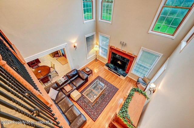 living room featuring hardwood / wood-style floors, a towering ceiling, and a premium fireplace