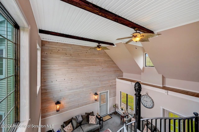 interior space with lofted ceiling with beams, ceiling fan, and wooden walls