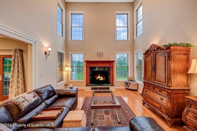 living room featuring a high end fireplace, a high ceiling, and light hardwood / wood-style flooring