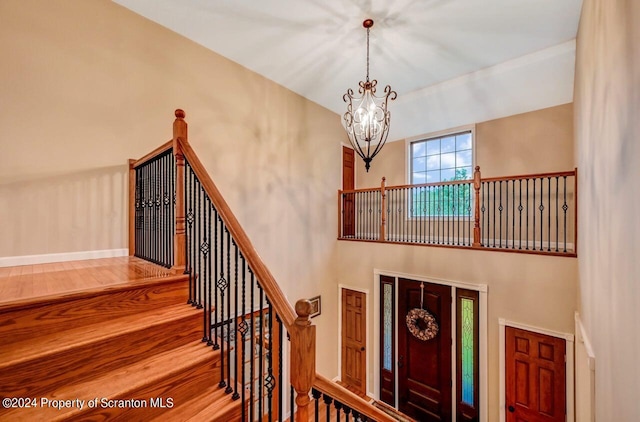 staircase with a notable chandelier and wood-type flooring