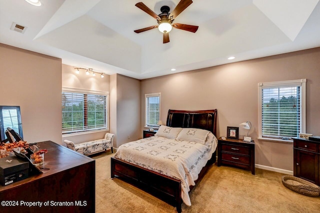 carpeted bedroom featuring a raised ceiling and ceiling fan