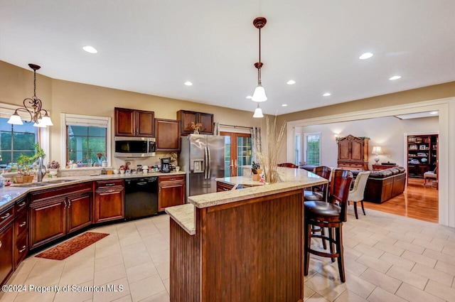 kitchen featuring a breakfast bar, sink, hanging light fixtures, appliances with stainless steel finishes, and a notable chandelier