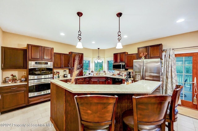 kitchen featuring a large island with sink, light tile patterned flooring, and appliances with stainless steel finishes