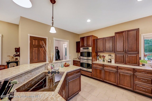 kitchen with double oven, light stone counters, stovetop, and decorative light fixtures