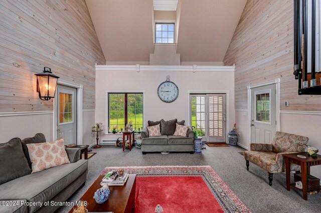 living room with carpet flooring, wood walls, high vaulted ceiling, and an inviting chandelier