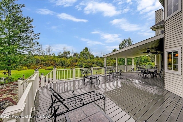 wooden terrace featuring ceiling fan and a lawn