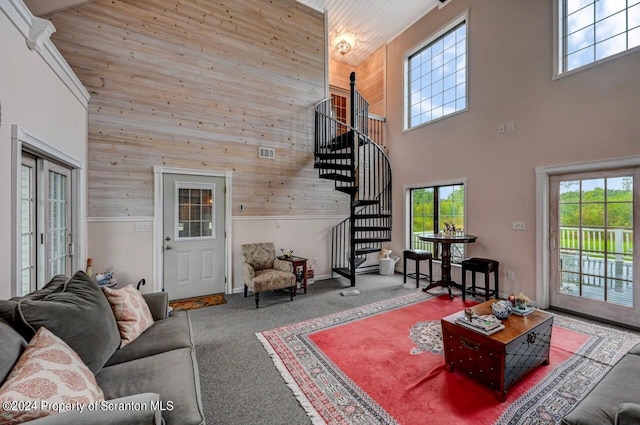 living room with carpet flooring, wooden walls, and a towering ceiling