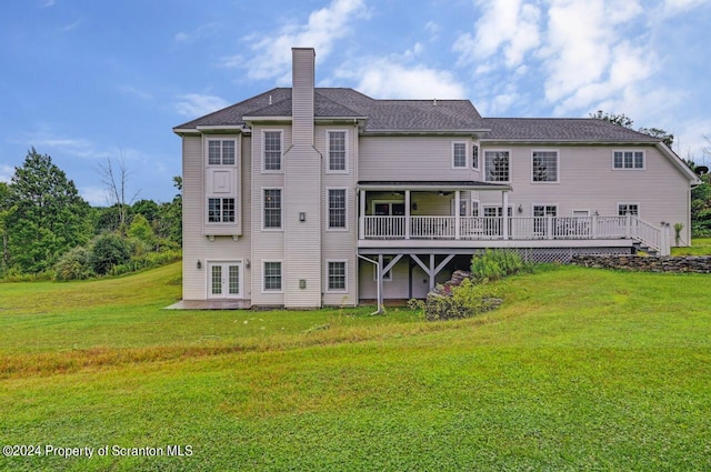 back of house featuring a lawn and a deck