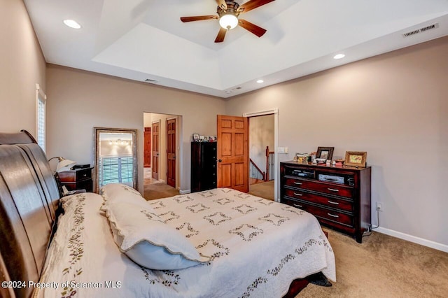 carpeted bedroom featuring a raised ceiling, ceiling fan, and a high ceiling