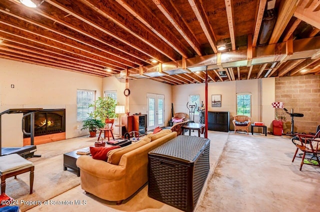 living room with a large fireplace, concrete floors, and french doors