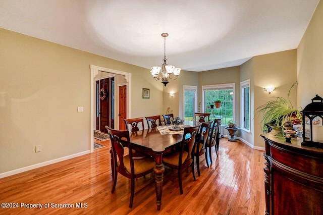 dining area with light hardwood / wood-style floors and an inviting chandelier