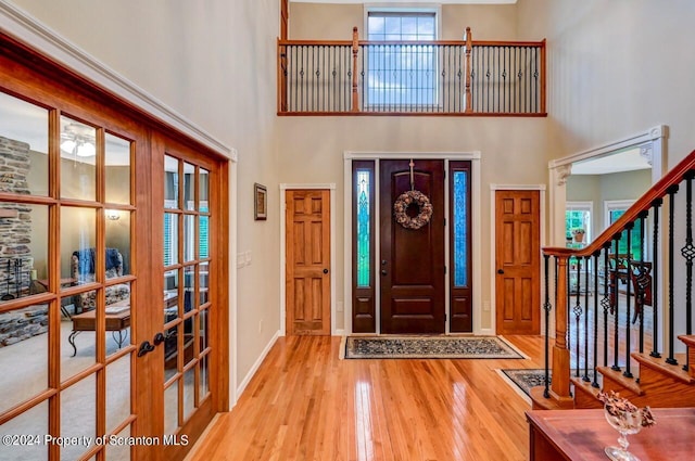 entryway with french doors, light hardwood / wood-style floors, and a high ceiling