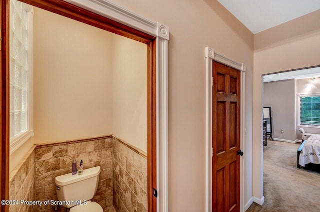 bathroom featuring toilet and tile walls