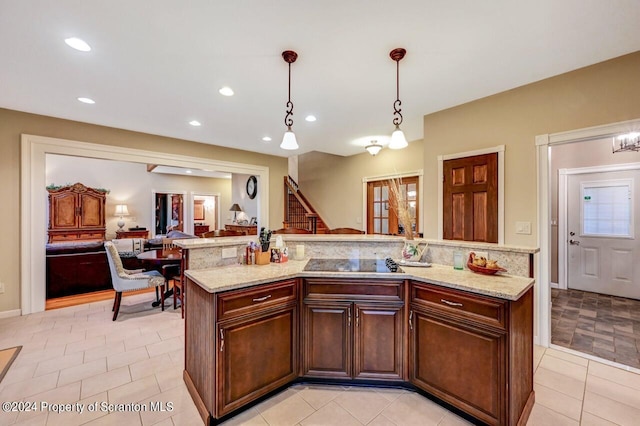 kitchen featuring light stone countertops, pendant lighting, light tile patterned floors, a center island, and black stovetop