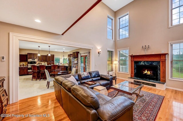 living room featuring a towering ceiling, a high end fireplace, and light hardwood / wood-style floors