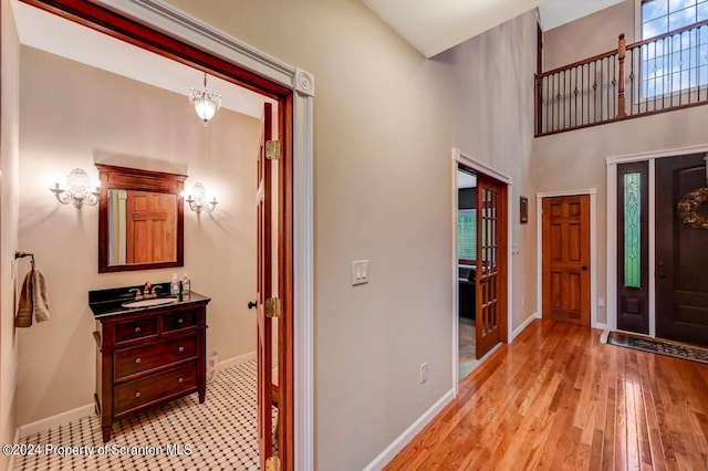 entryway featuring light wood-type flooring, a towering ceiling, and sink