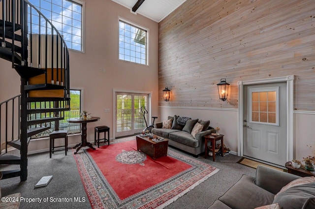 living room with carpet flooring, wood walls, and a towering ceiling