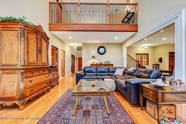 living room with light hardwood / wood-style flooring and a towering ceiling