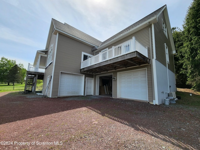 rear view of house featuring a garage and a wooden deck