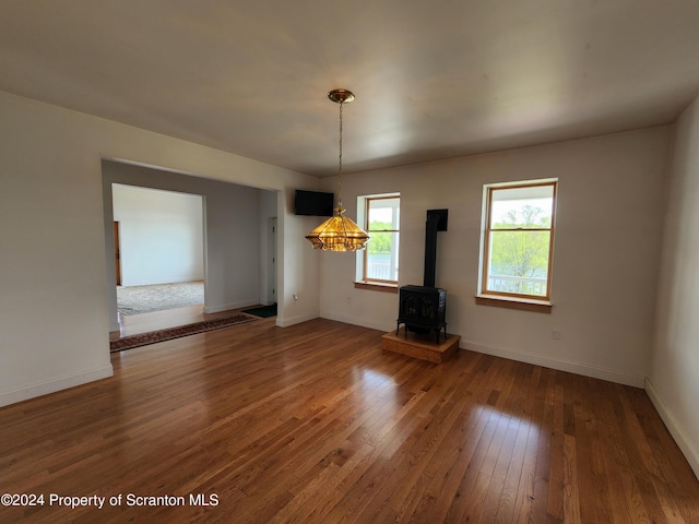 unfurnished dining area featuring hardwood / wood-style floors and a wood stove