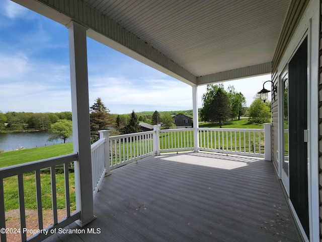 wooden deck with a water view and a yard