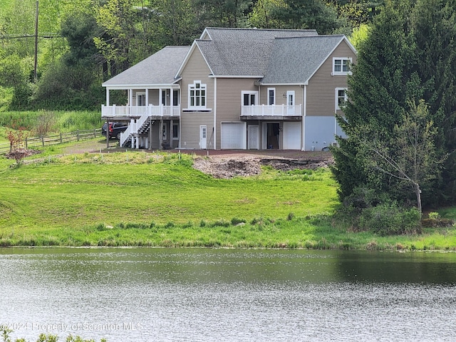 rear view of property featuring a deck with water view and a garage