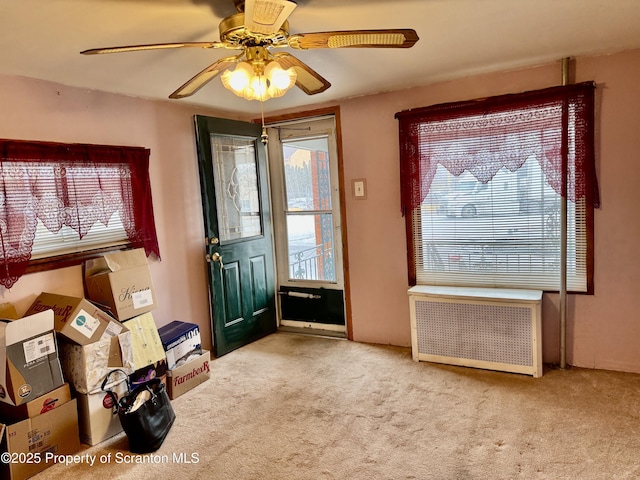 carpeted entrance foyer with radiator heating unit and a ceiling fan