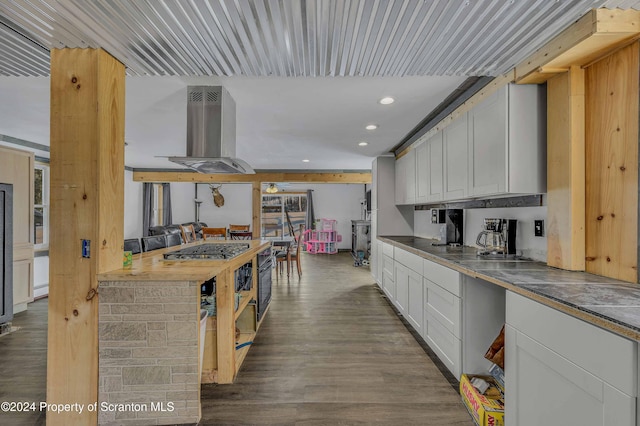 kitchen with white cabinetry, wall chimney range hood, dark hardwood / wood-style floors, oven, and stainless steel gas stovetop