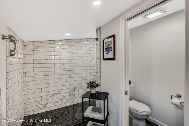 bathroom with a tile shower and toilet